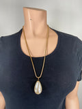 Long gold necklace with a single faux pearl drop.